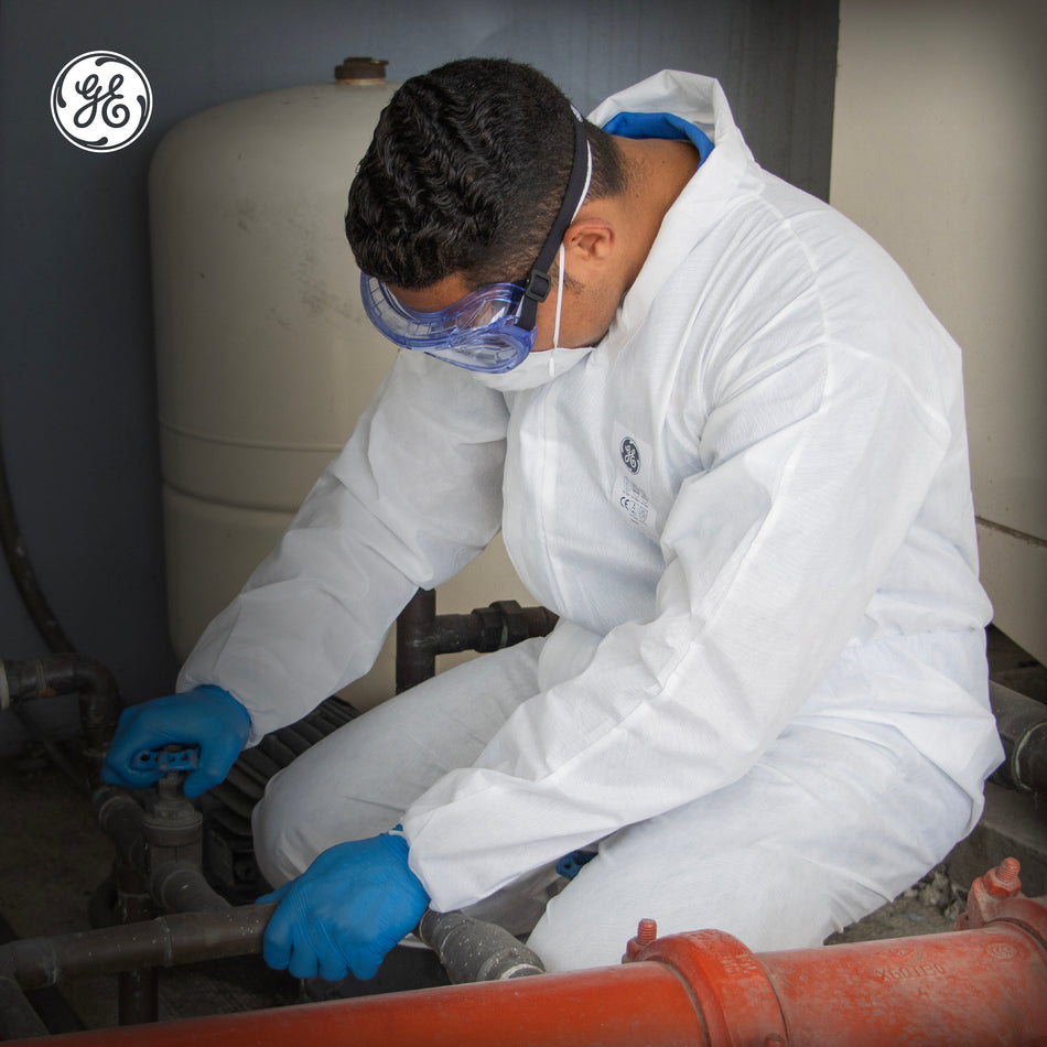 GE SMS protective coverall in industrial use with safety goggles, mask, and gloves for light splash and particle protection, SKU GW900.