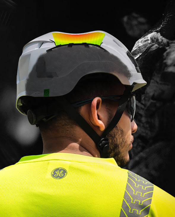 Worker wearing a GE safety helmet with crushed Koroyd end-of-life indicator visible